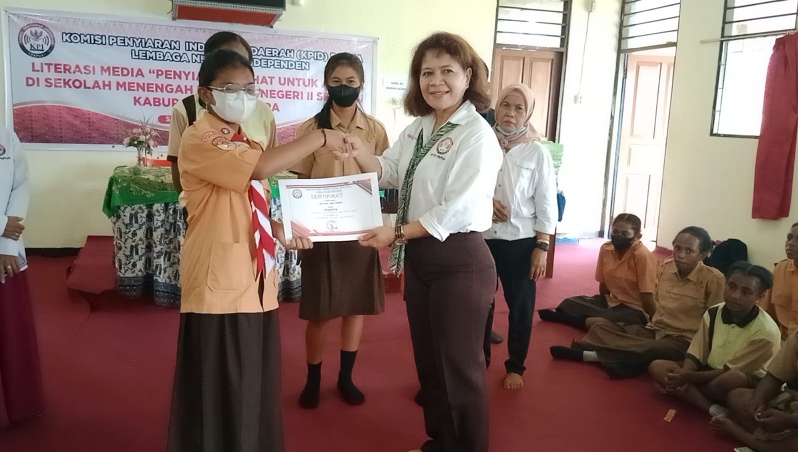 Ketua KPID Papua, Christine Rusni Abaidata ketika menyerahkan sertifikat kepada salah satu perwakilan pelajar, usai kegiatan Literasi Media, di SMPN 2 Sentani